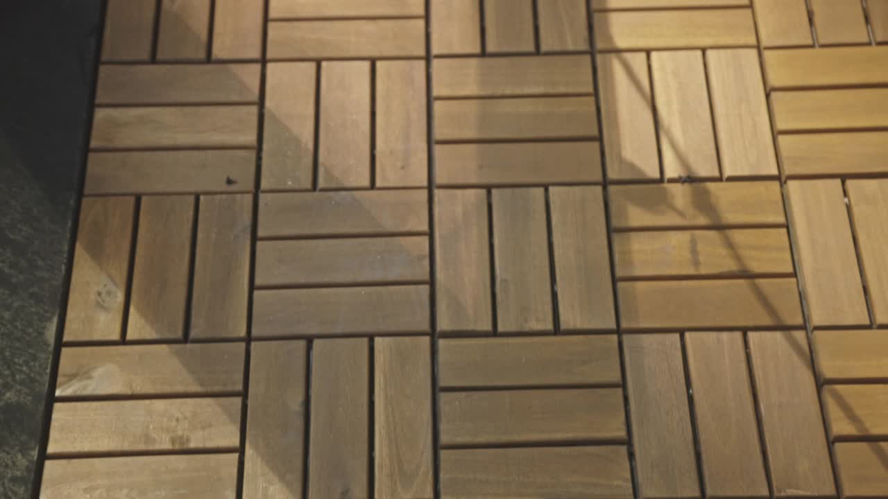 una vista de los azulejos de patio de madera que cubren el suelo al aire libre entrelazados