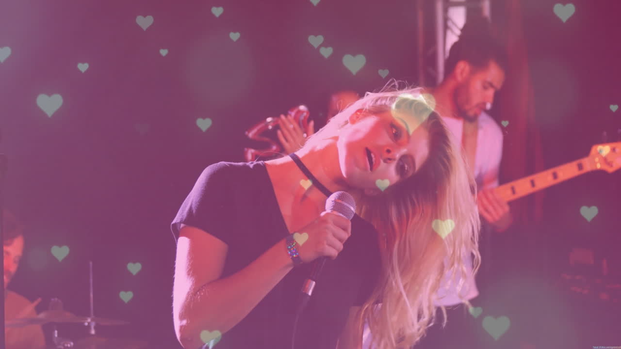 female lead vocalist leaning back singing into microphone on music stage, with heart bokeh overlays