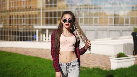 Hermosa-Joven-Con-Rastas-Bailando-En-Un-Parque.-Hermosa-Mujer-En-Jeans-Y-Gafas-De-Sol-Escuchando-Música-Y-Bailando