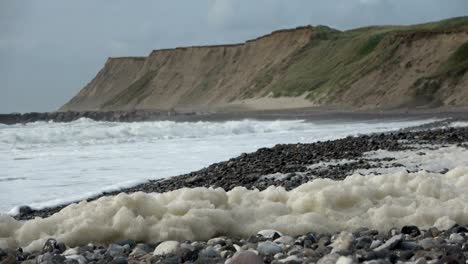 algae foam in storm on the beach, sandy beach with waves, north sea, jütland, sondervig, denmark, 4k