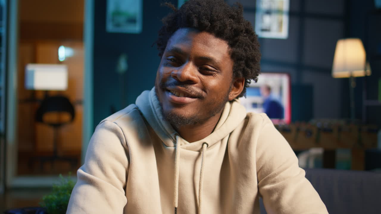 African American adult enjoying the comfort of his loft apartment while working remotely on his laptop. An excellent representation of productivity and modern work from home trends. Camera B.