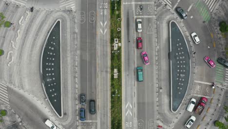 vista aérea de pájaros de una rotonda con coches, bicicletas, autobuses y gente caminando