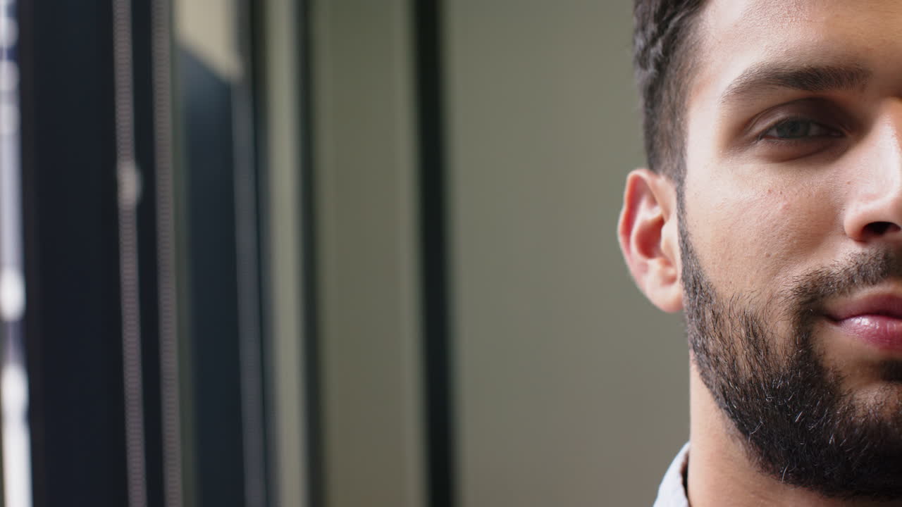 Uomo sicuro di sé con la barba in piedi al chiuso, con un'espressione pensierosa e concentrata, spazio per il testo