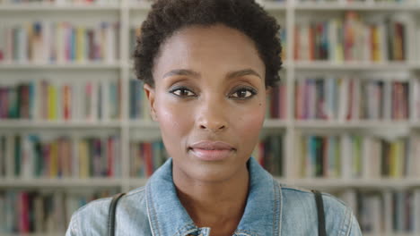 Portrait-African-American-woman-student-smiling-bookshelf-library-university