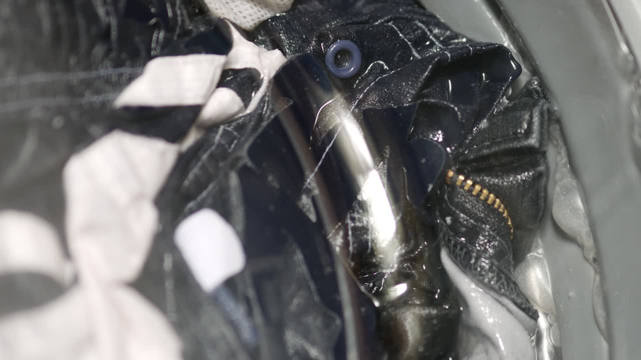 las cosas están girando en el tambor de la máquina de lavar moderna. puerta de vidrio de landromat