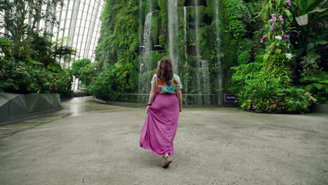 happy tourist enjoying the botanical garden with indoor waterfall of cloud forest in gardens by the bay, singapore