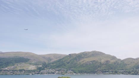 an airplane taking off in queenstown shot from the ground revealing the lake wanaka and resdence buildings town