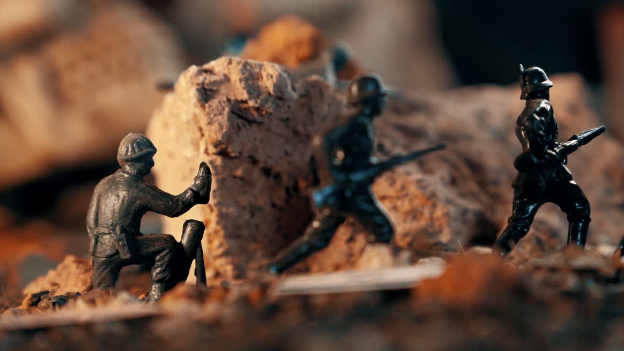 Soldatini di plastica in miniatura che combattono su un diorama di un campo di battaglia desolato. Un teschio umano giace tra lo sporco e le rocce in una scena a tema bellico