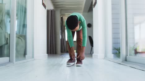 african american boy standing in hallway tying his shoes