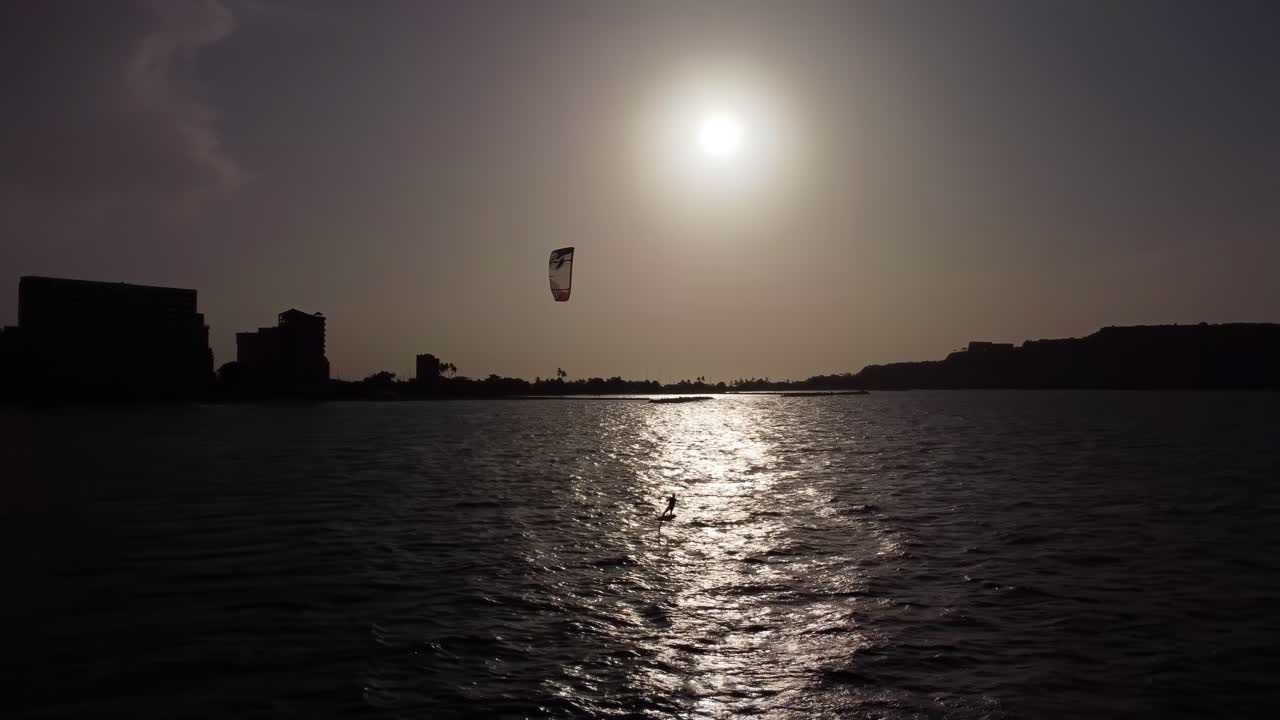 해질녘 해변에서 카이트서핑을 연습하는 운동선수의 항공 촬영 장면