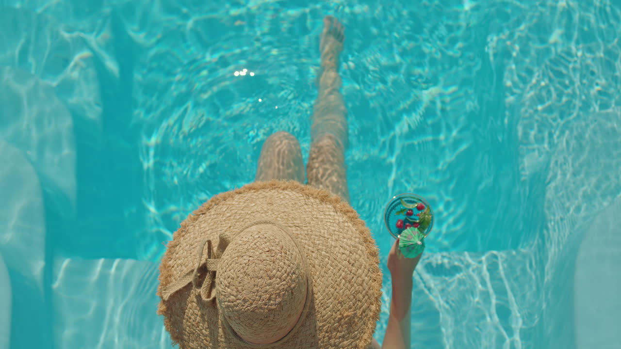 Frau entspannt sich im Pool mit einem Getränk