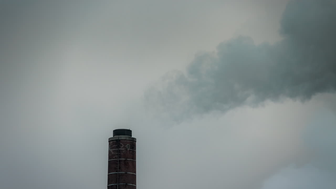 Individual chimney emitting smoke, close up timelapse against grey sky