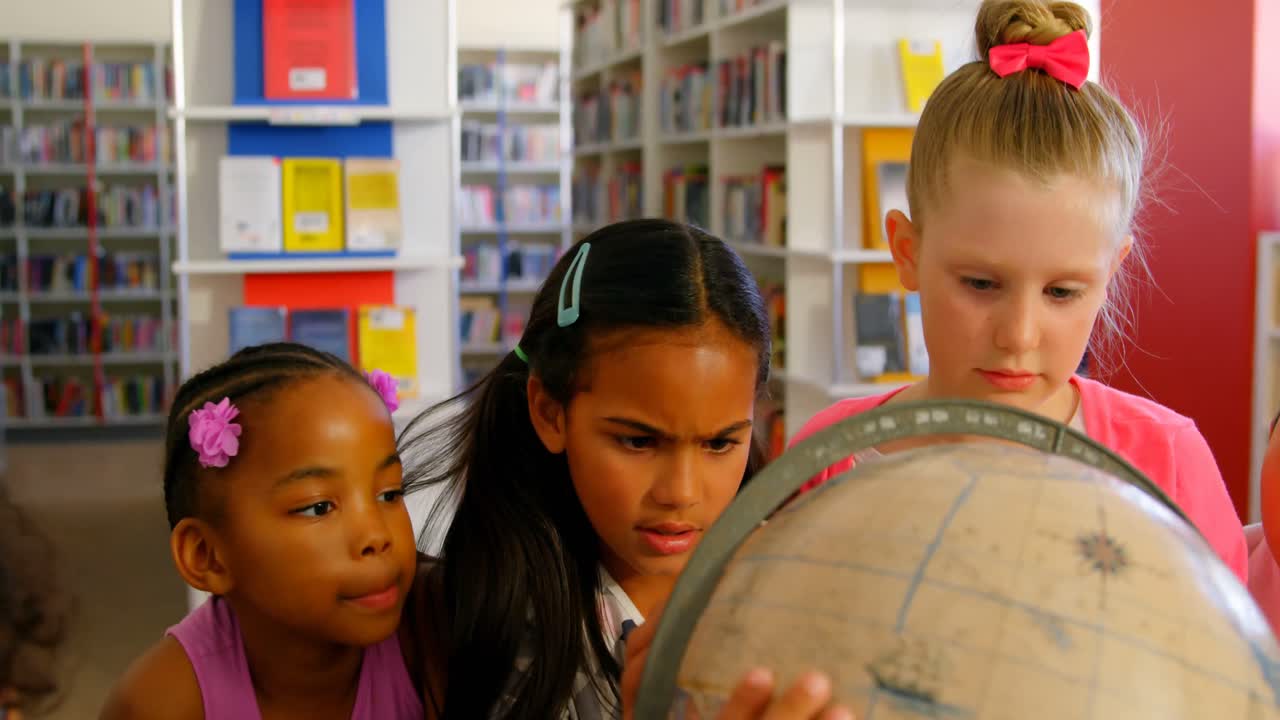 Schoolkids looking at globe in the school library 4k