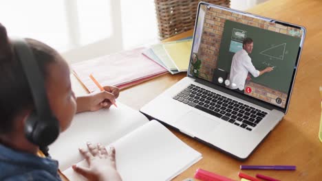 african american girl using laptop for online lesson with biracial male teacher on screen
