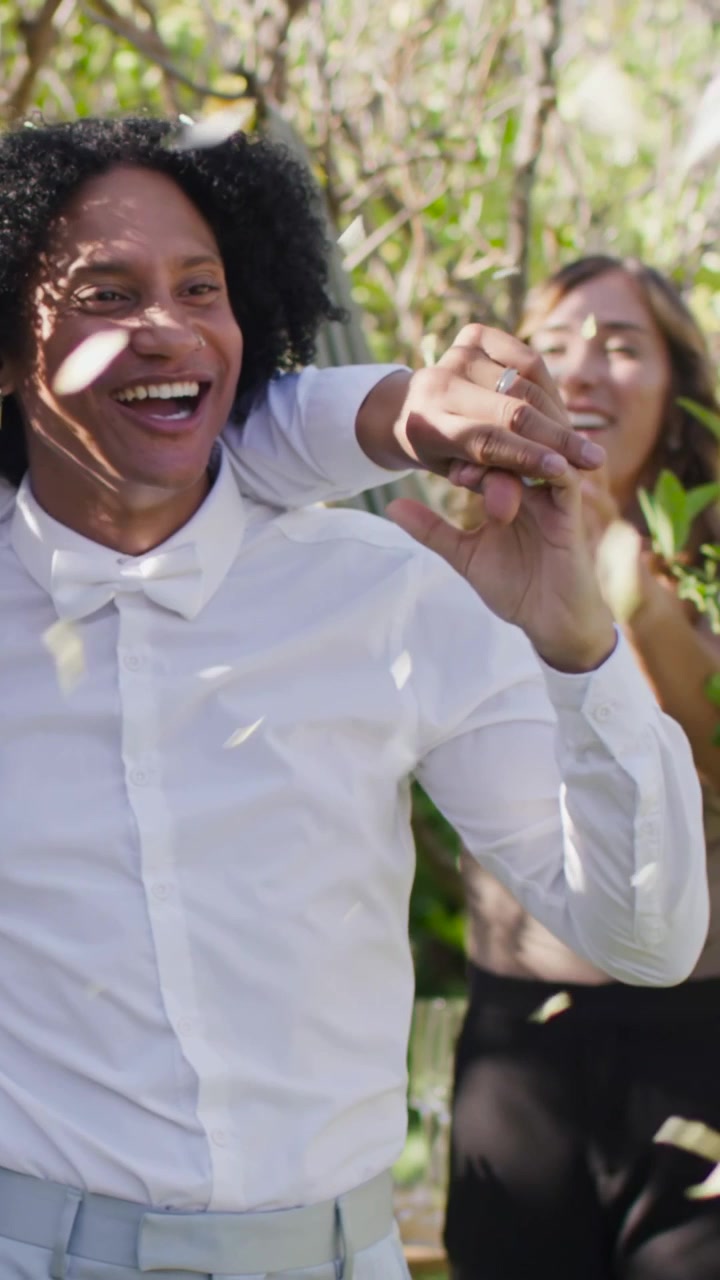 Video verticale: Amico che mette il braccio sulla spalla e guida un uomo con papillon bianco che volteggia tra i coriandoli della festa.