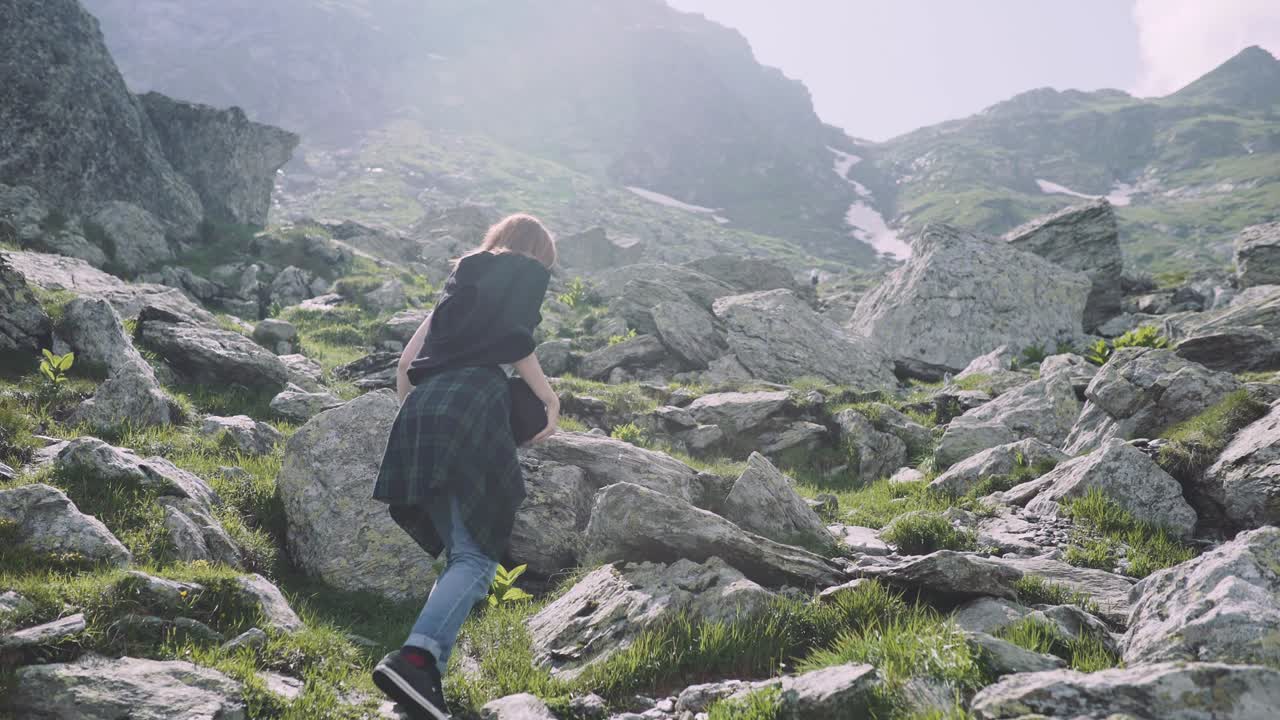una joven excursionista sube montañas con una cámara fotográfica. transfagarasan, montañas de los cárpatos en rumania