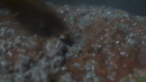 cuchara de madera revolviendo salsa boloñesa en carne picada