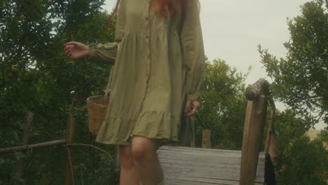woman walking through an orange grove on a wooden bridge