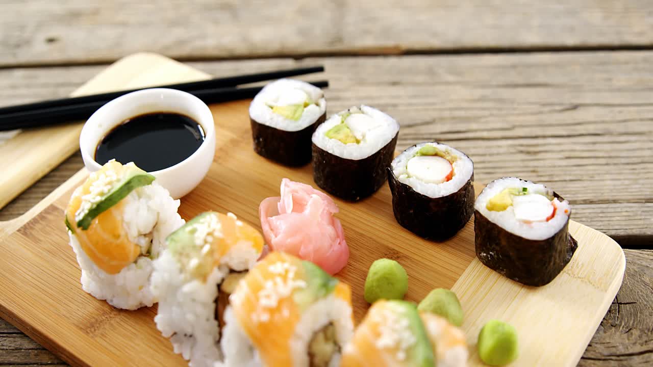 primer plano de varios sushi en bandeja con salsa
