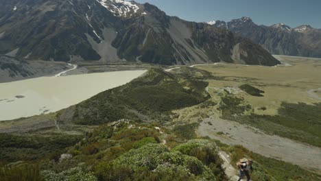 woman going up sealy tarns mountain trail on perfect sunny day, mount cook national park