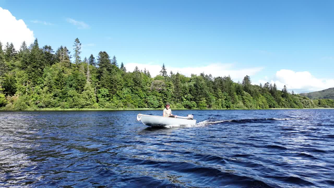 Man operating a compact fiberglass boat with outboard motor on lake