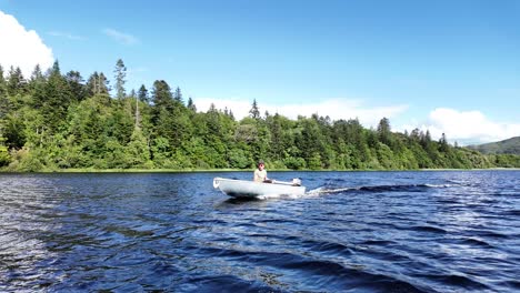 man operating a compact fiberglass boat with outboard motor on lake