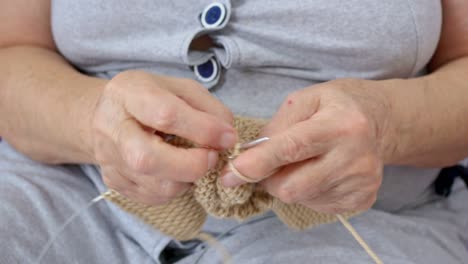 primer plano de la mano de una abuela tejiendo calcetines para sus queridos nietos. hobby en la edad avanzada para las mujeres, tejer usando dos agujas de tejer. las manos de la anciana dañadas por la artritis