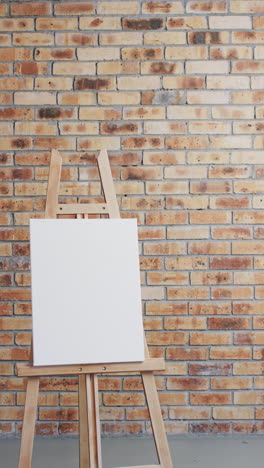 vertical video of white canvas sign with copy space on wooden easel and brick wall background