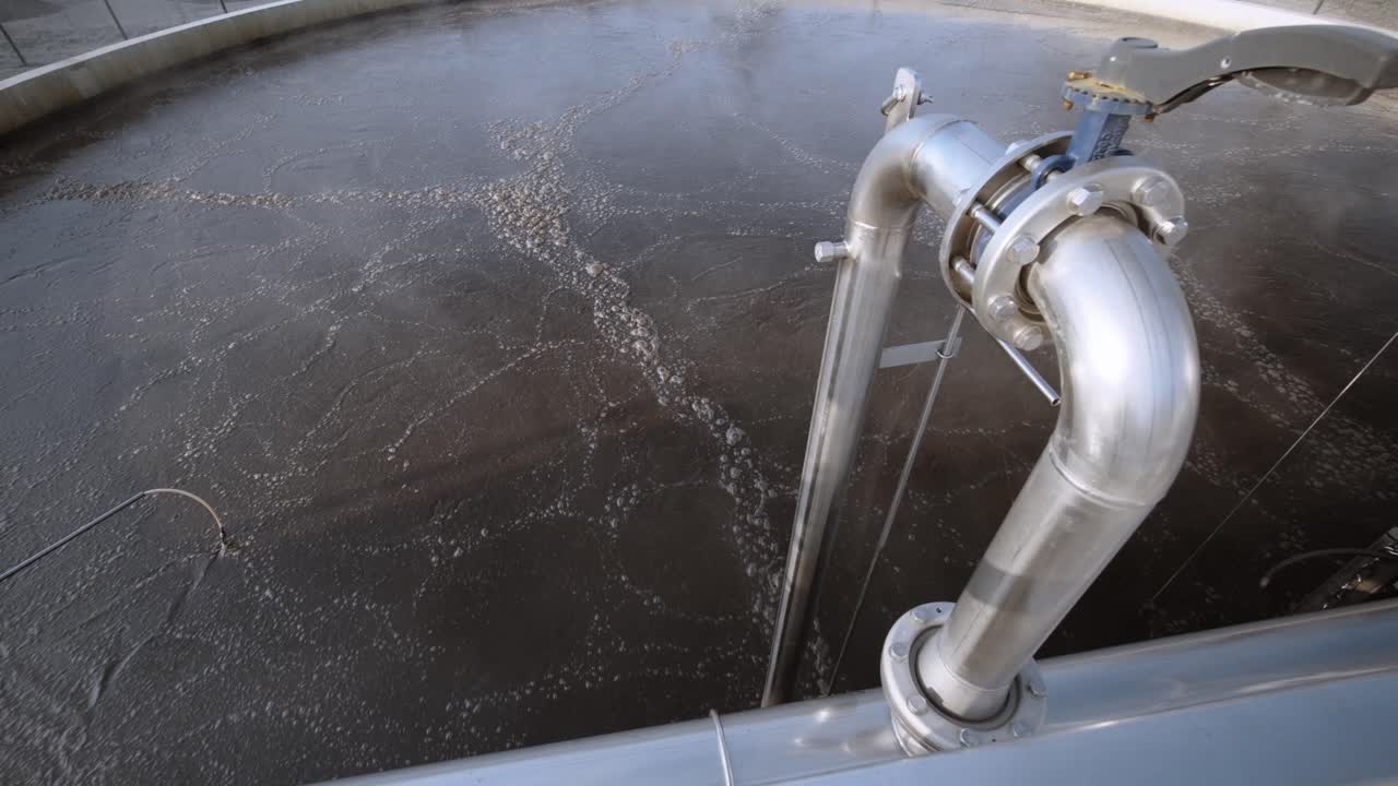 Industrial setting with a large metal tank and pipes, symbolizing industry and manufacturing, dominated by dark metallic colors.