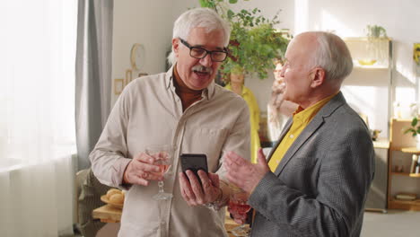hombres mayores usando teléfonos inteligentes y charlando en una fiesta en casa