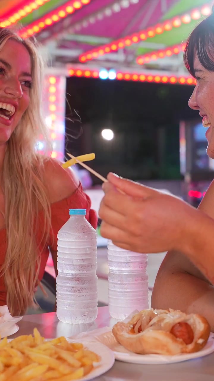 Due giovani donne che mangiano fast food a un parco divertimenti
