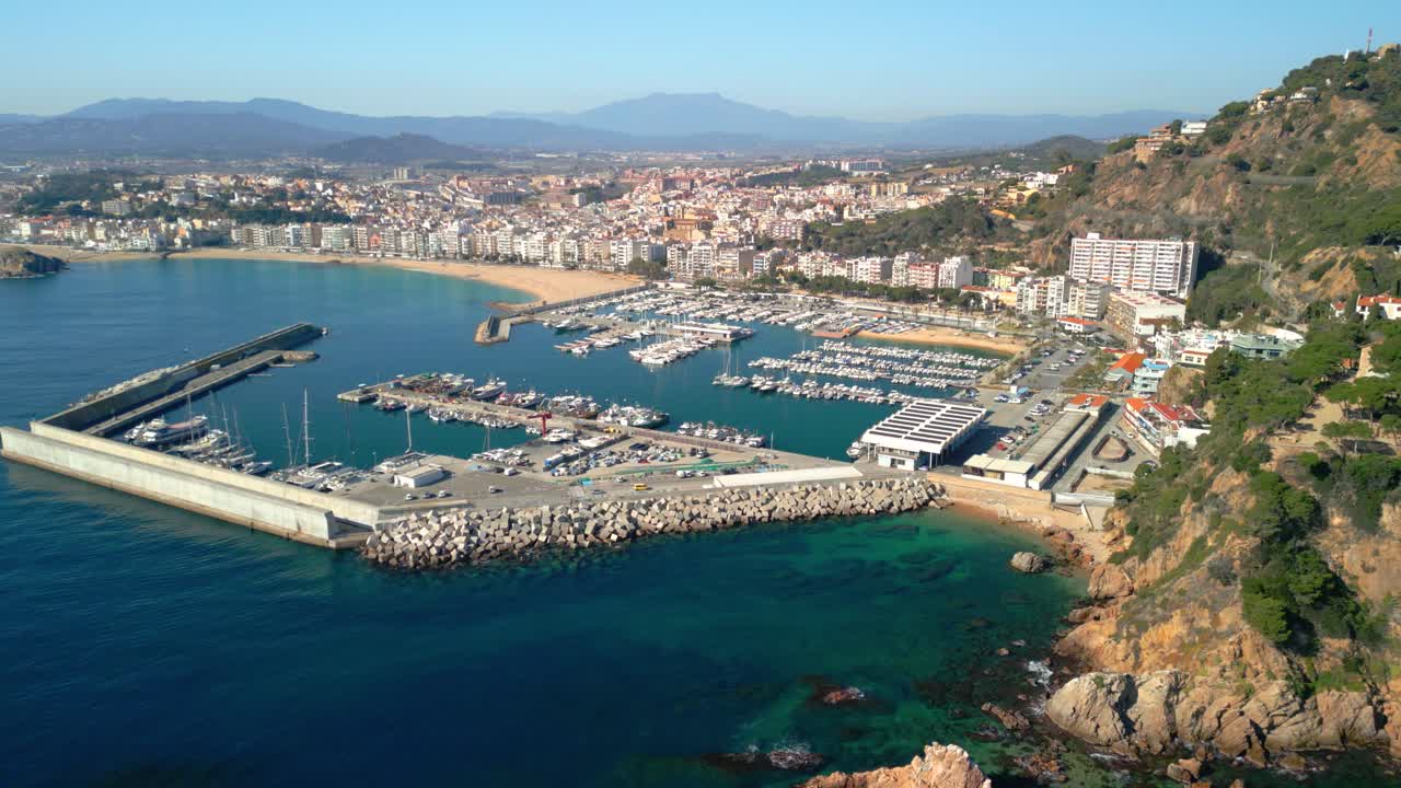 Blanes panoramic aerial perspective capturing vibrant blanes harbor nestled along picturesque costa brava coastline, revealing mediterranean landscape with marina, boats, and scenic urban backdrop