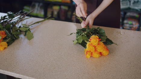 florist arranging orange and yellow roses