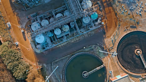 aerial footage moving towards a large industrial chemical plant, showing pipelines, metal structures, cooling towers and chemical storage