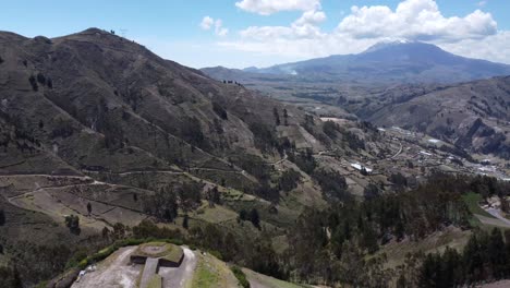 Breathtaking-drone-flight-revealing-majestic-Cochapamba-mountains,-highlighting-the-imposing-Illinizas-volcano-in-the-background