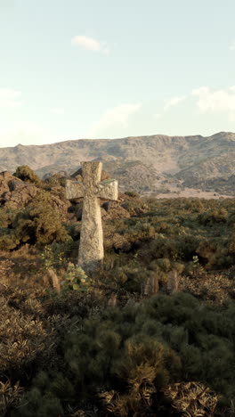 stone cross in the desert with mountains in the background