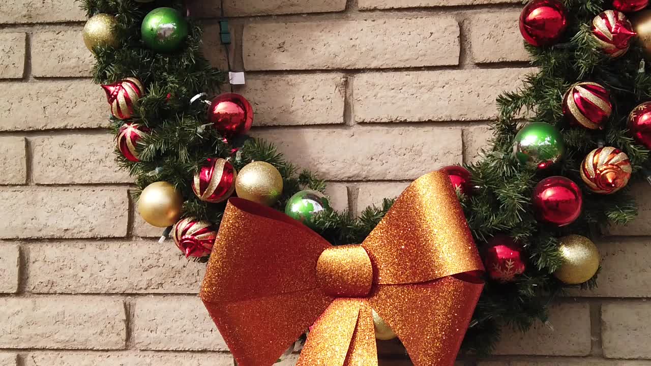 inclina hacia arriba desde un lazo dorado brillante hasta una corona navideña completamente decorada