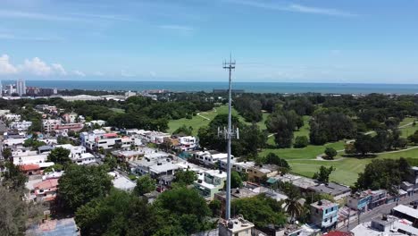 Aerial-drone-view-of-residential-houses-showing-a-communications-antenna-in-panoramic,-UHD-video-in-beautiful-blue-sky