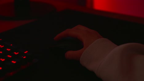 anonymous hacker in a dark red room using a mouse