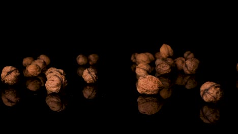 Walnuts-Falling-On-Black-Surface,-English-Shelled-Walnuts,-Close-Up
