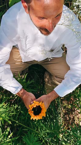 man holding sunflower in a garden