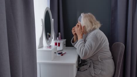 senior woman applying eye mask in bathroom