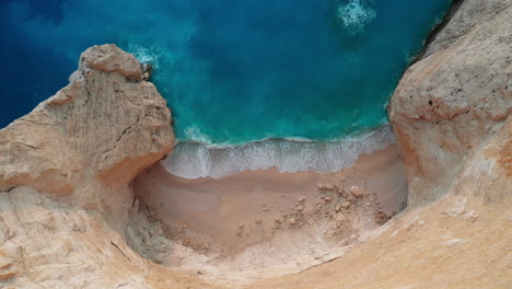 Downward-angle-drone-shot-of-empty-white-sand-beach-at-Navagio-Beach