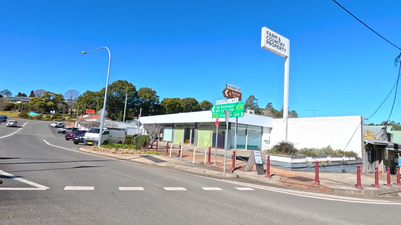 Una prospettiva grandangolare da dashcam cattura un viaggio soleggiato attraverso una tranquilla cittadina rurale australiana.