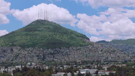 tilt up to telecom towers on hilltop with houses and greenery in foreground