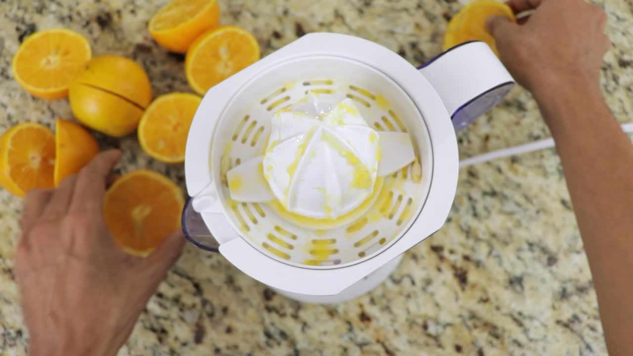 exprimir jugo de naranja fresco con una máquina en la cocina, vista en primera persona