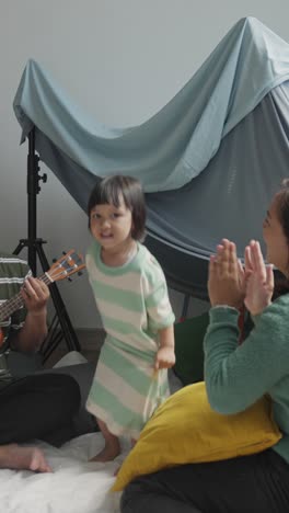 vertical video of asian family having fun, singing and dancing together in a tent at home