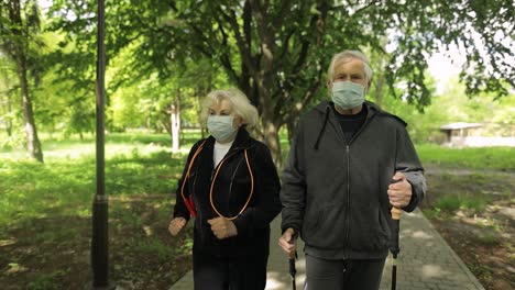 elderly couple walking in park wearing face masks