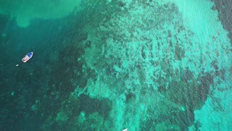 Serenity-Aerial-View-of-Boats-in-the-Ocean-with-Coral-Reef,-tilt-up-reveal-Los-Roques-village