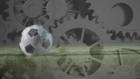 Animation-of-cogs-spinning-and-processing-over-football-player-kicking-ball